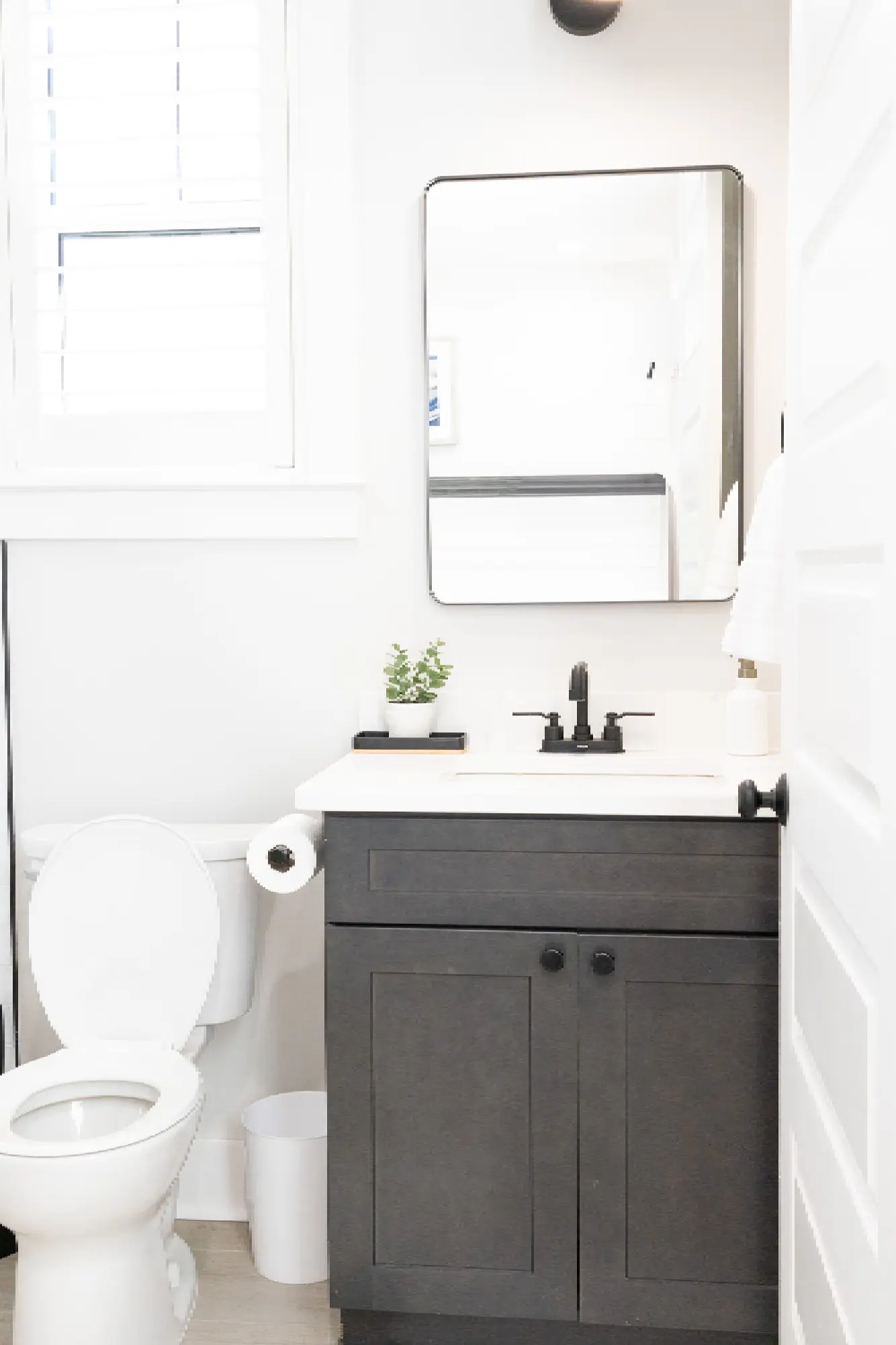 A crisp, modern bathroom featuring clean white walls and a dark charcoal vanity professionally painted and finished by Grayton Painting.