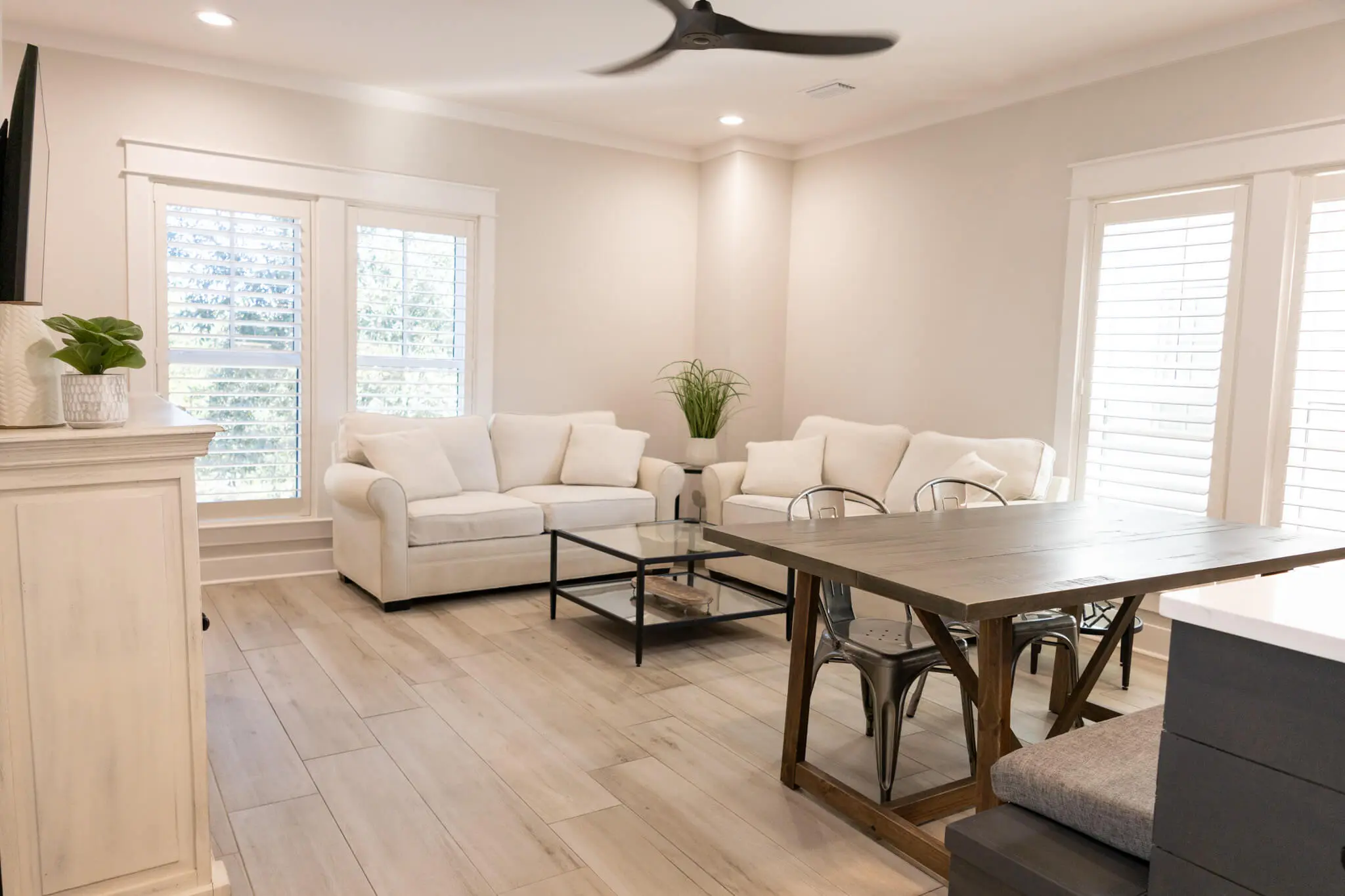 A spacious, light-filled living area featuring a modern wood dining table and crisp white walls, expertly finished by Grayton Paint Company.