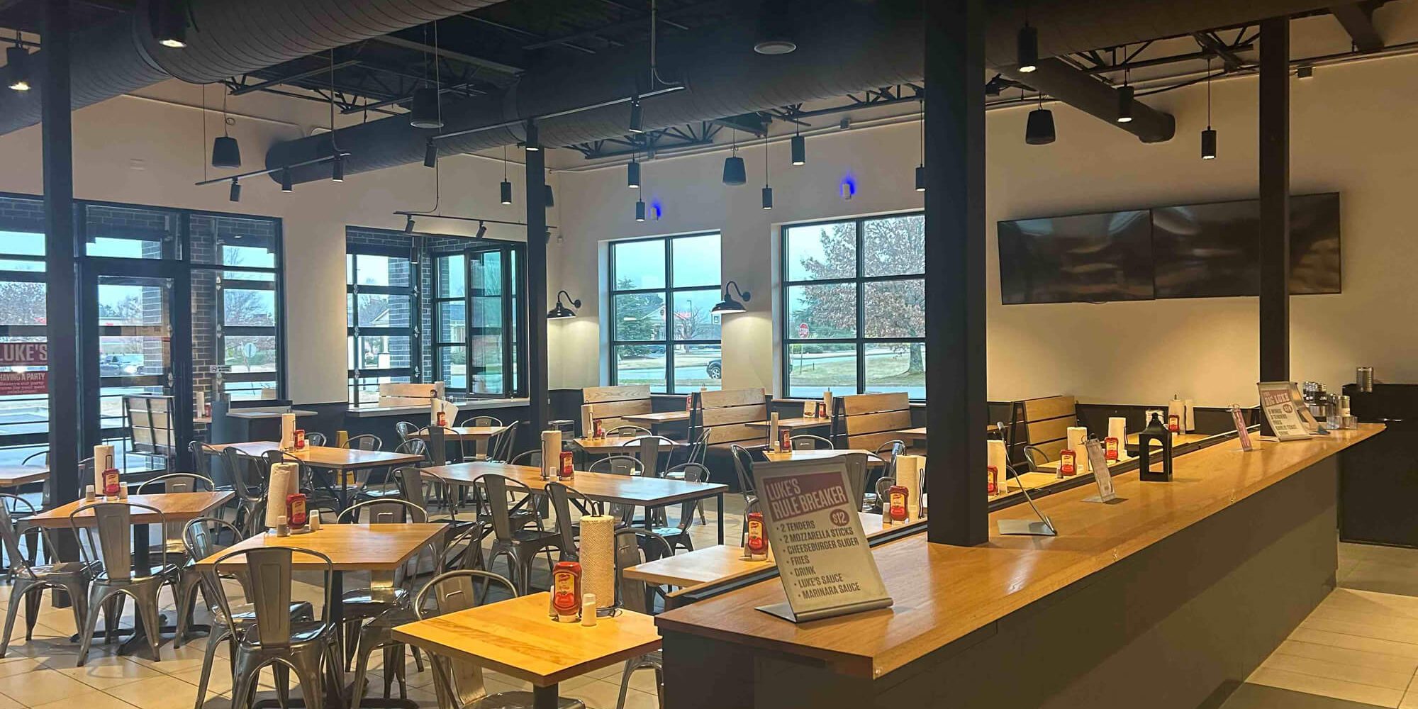 Clean, modern restaurant interior with freshly painted walls, open seating layout, wood tables, and exposed ceiling details.