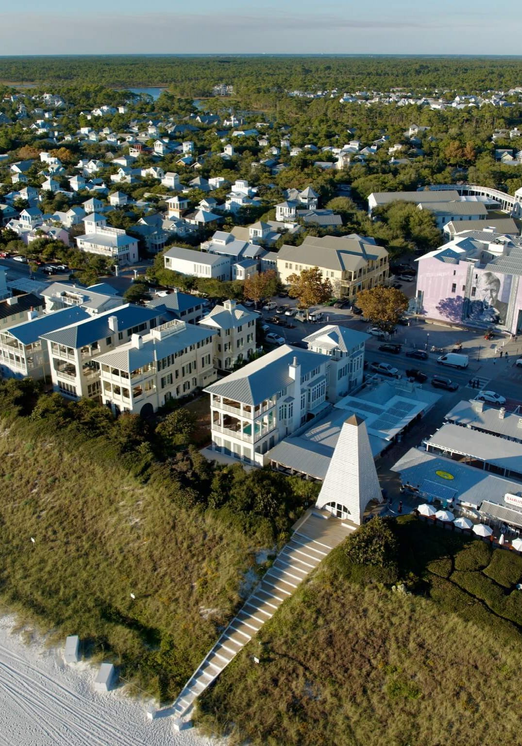 Aerial view of Seaside, Florida showcasing coastal homes, beachfront dunes, and the town center along the Gulf Coast
