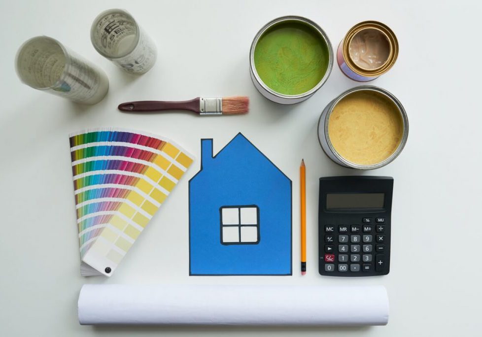 Painting supplies laid out with color swatches, paint cans, brush, calculator, and house graphic illustrating what to know before repainting your home